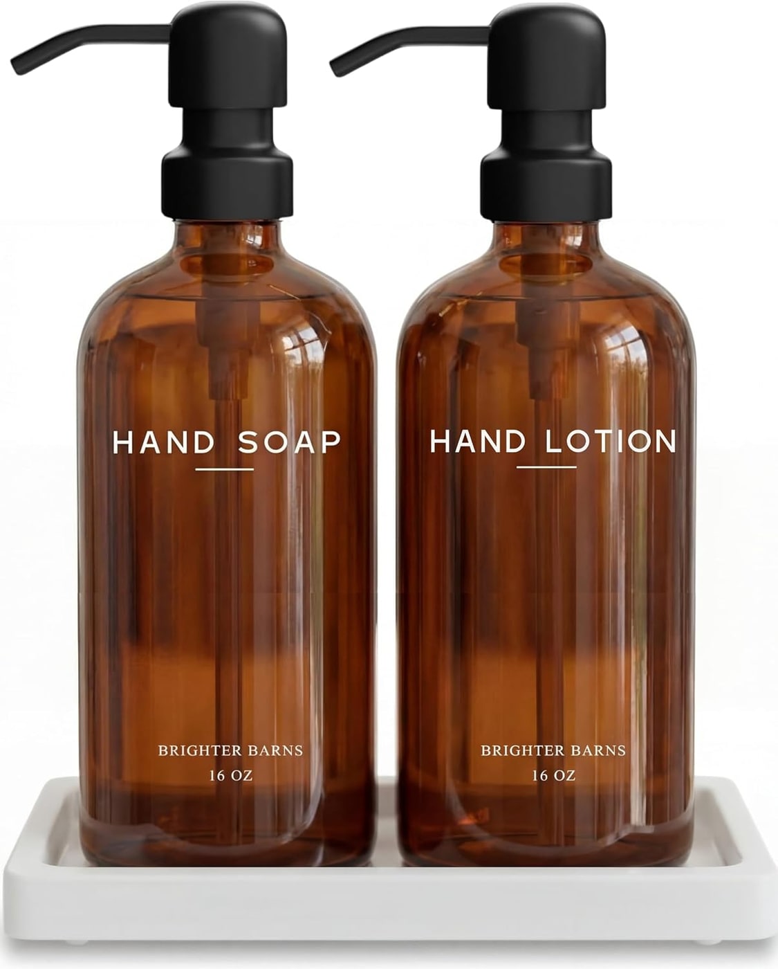 Amber glass bathroom soap and lotion dispensers with brushed stainless steel pumps on a white ceramic tray