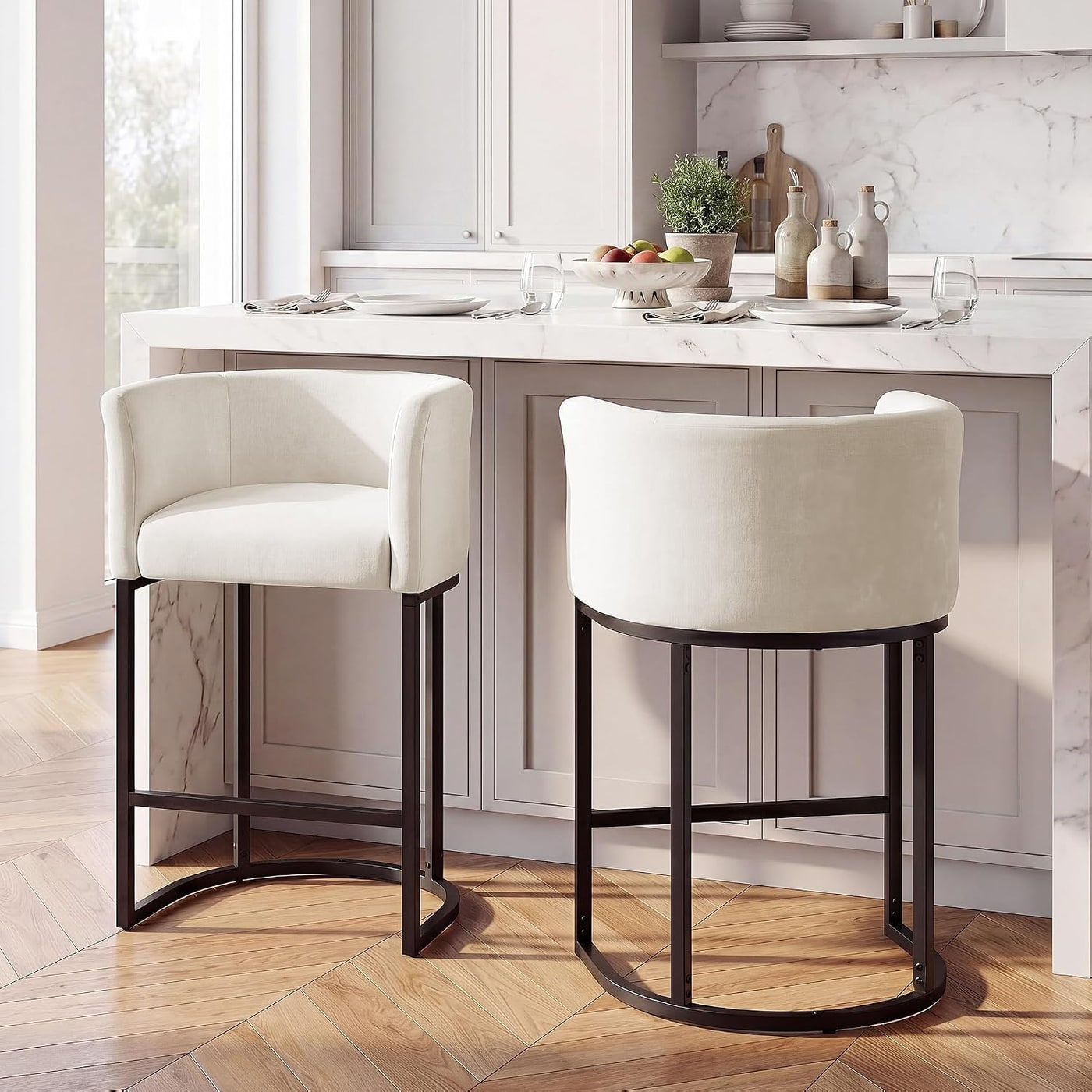 Two off-white chenille counter stools with barrel backs, arms, and reinforced metal legs