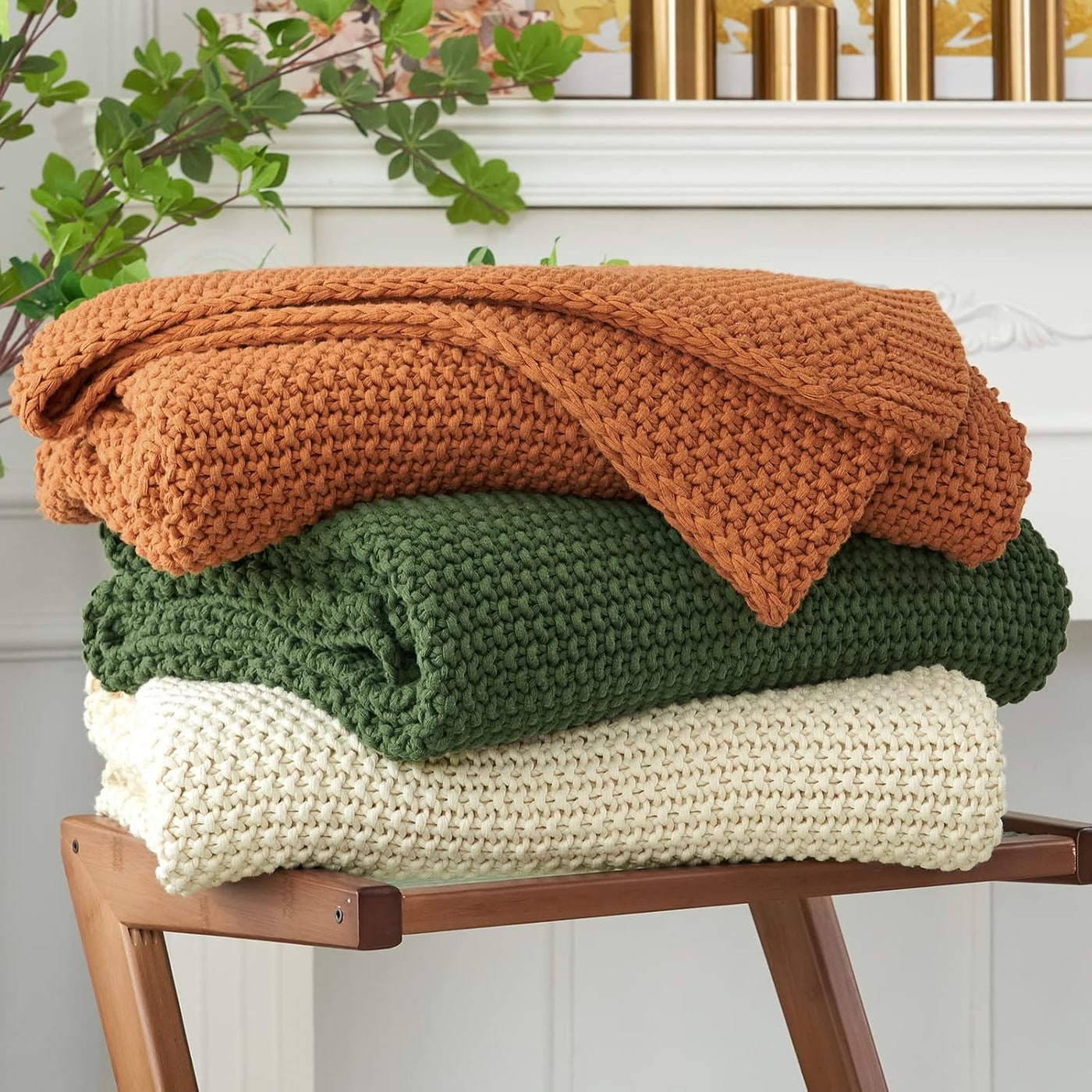 Chunky cable knit throw blanket in burnt orange, draped to show its thick cables and soft, nubby texture.