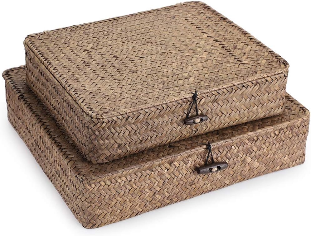 Set of two handwoven seagrass storage baskets with matching lids, stacked together on a light surface
