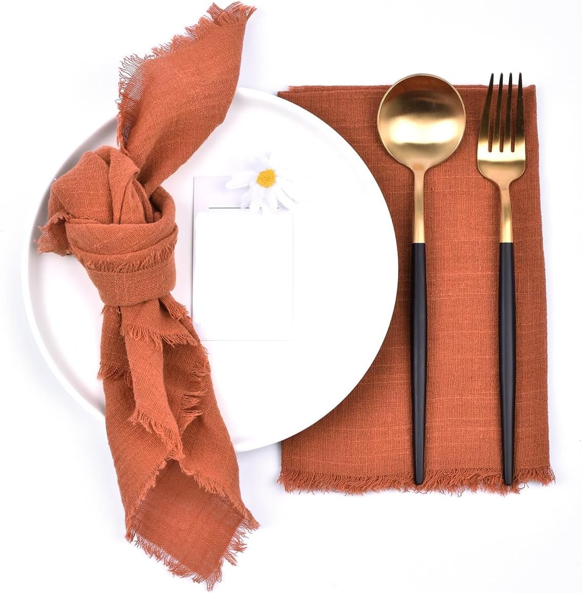 Set of six terracotta cotton-linen napkins with hand-pulled fringe, folded on a white background