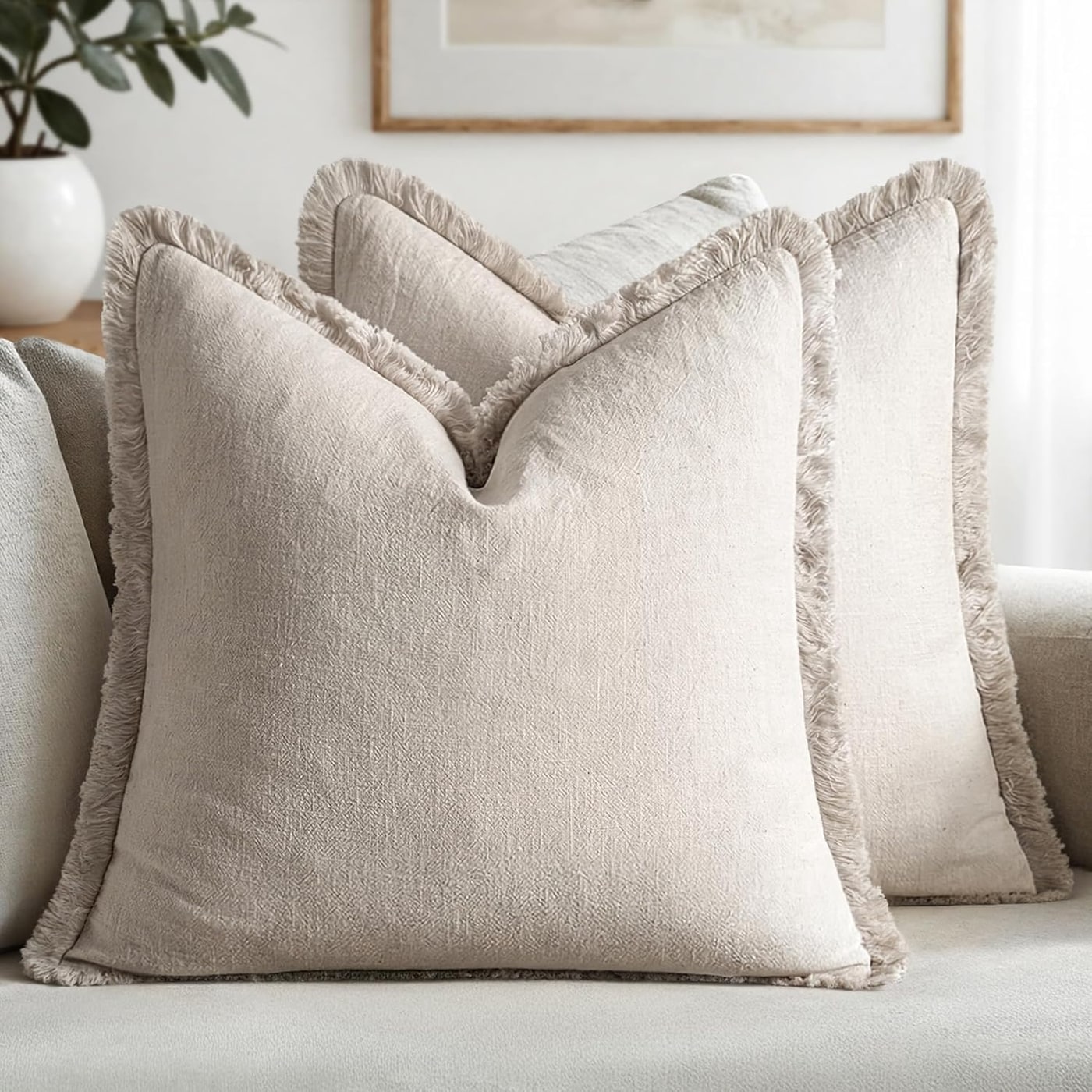 Pair of natural beige linen throw pillow covers with short fringe trimming, shown on a neutral background.