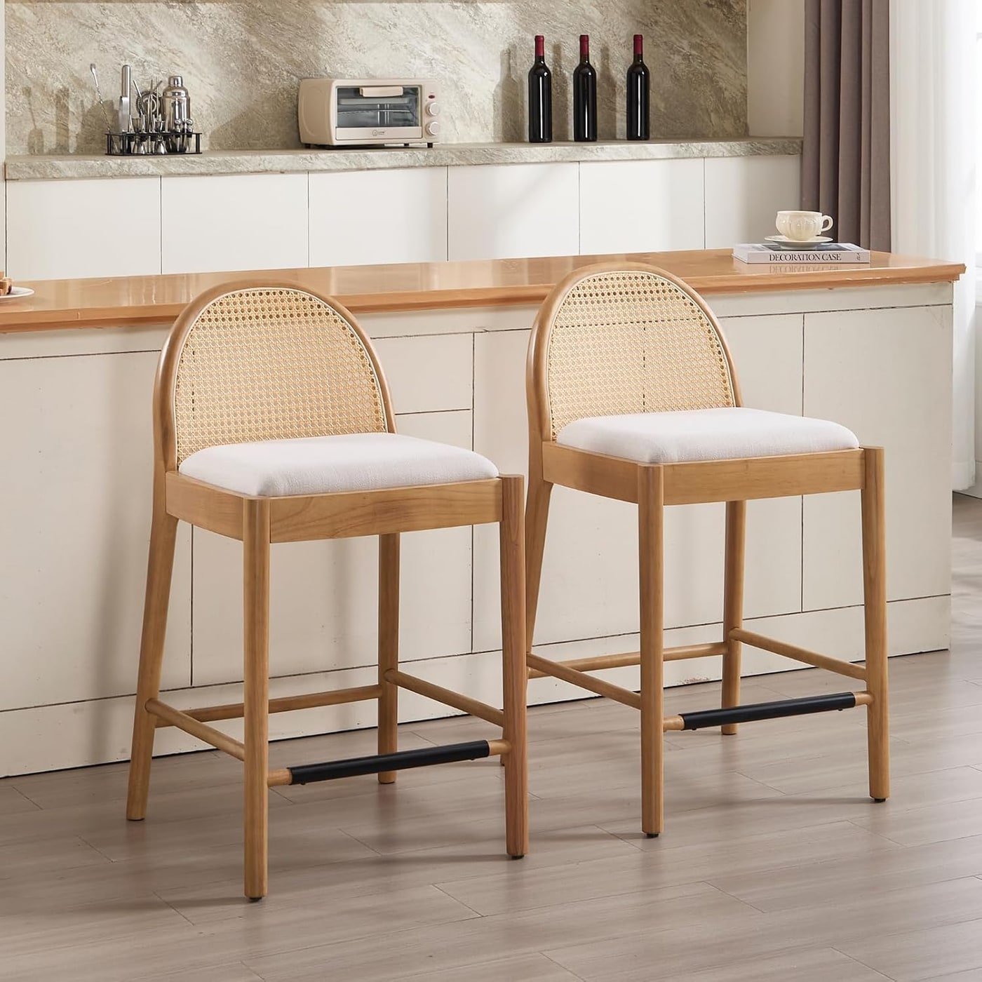 Pair of handwoven rattan counter stools with solid wood legs and linen seat cushions, arranged side by side.