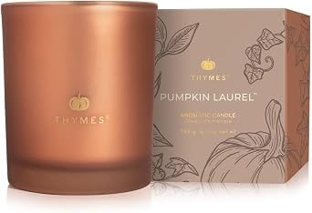 Burnt orange frosted glass candle jar with a metallic gold accent band, filled with creamy wax