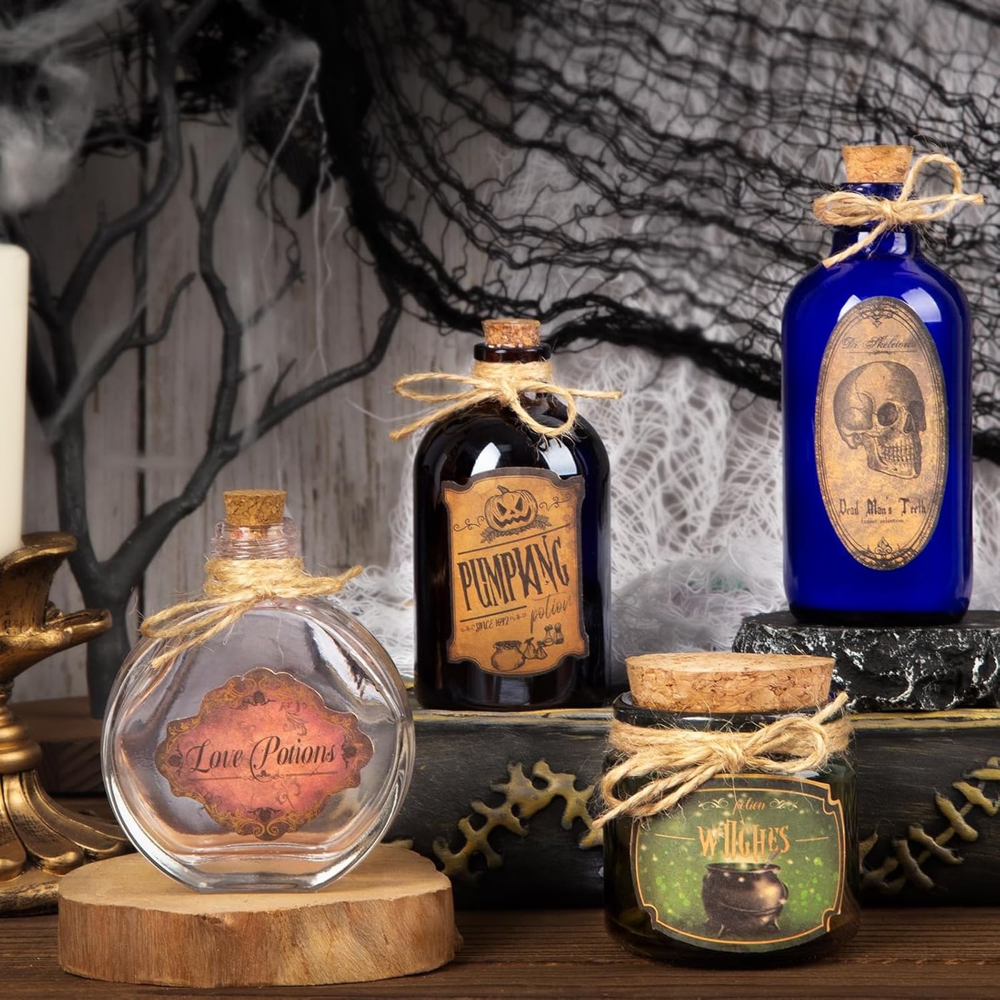 Set of four small vintage-style glass potion bottles in clear, blue, green, and brown with cork stoppers, Halloween labels, and jute twine